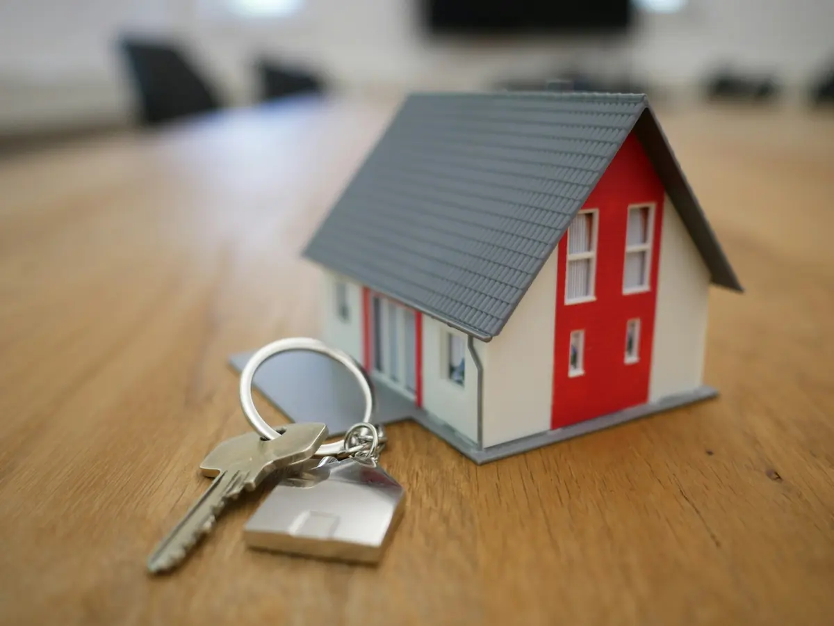 A small model house with keys, representing property and maintenance.