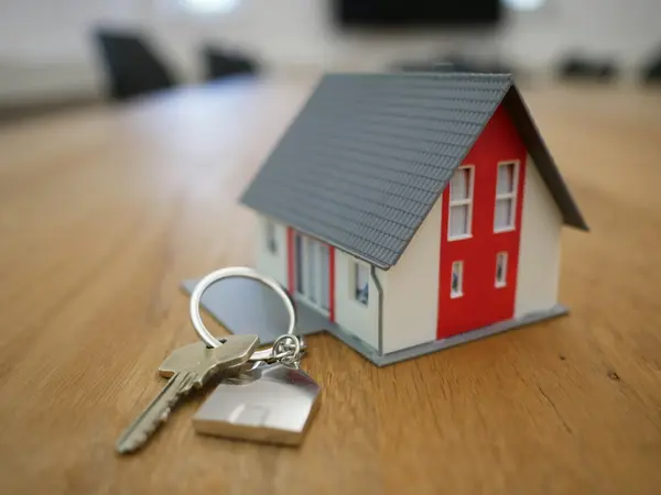 A small model house with keys, representing property and maintenance.